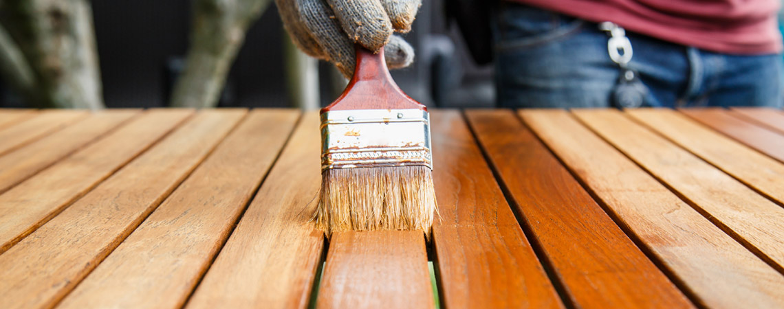 Wooden garden table being varnished with a brush